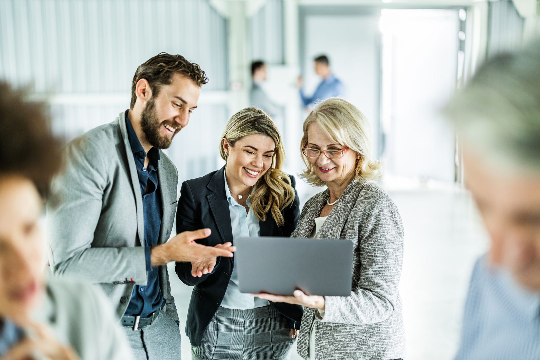 Young happy business colleagues and their mature manager working on a computer in the office.