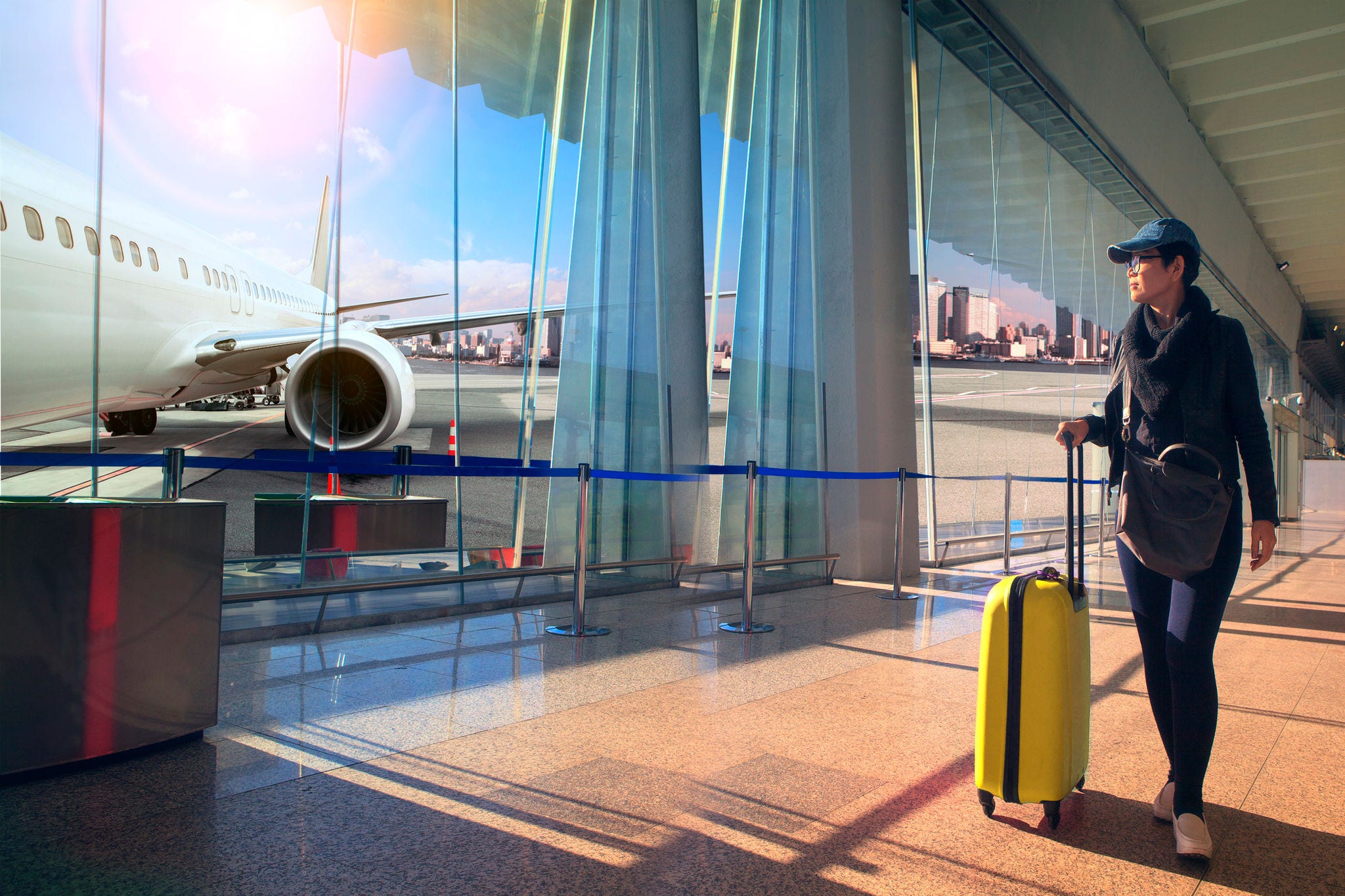 traveling woman and luggage walking in airport terminal and air plane flying outside