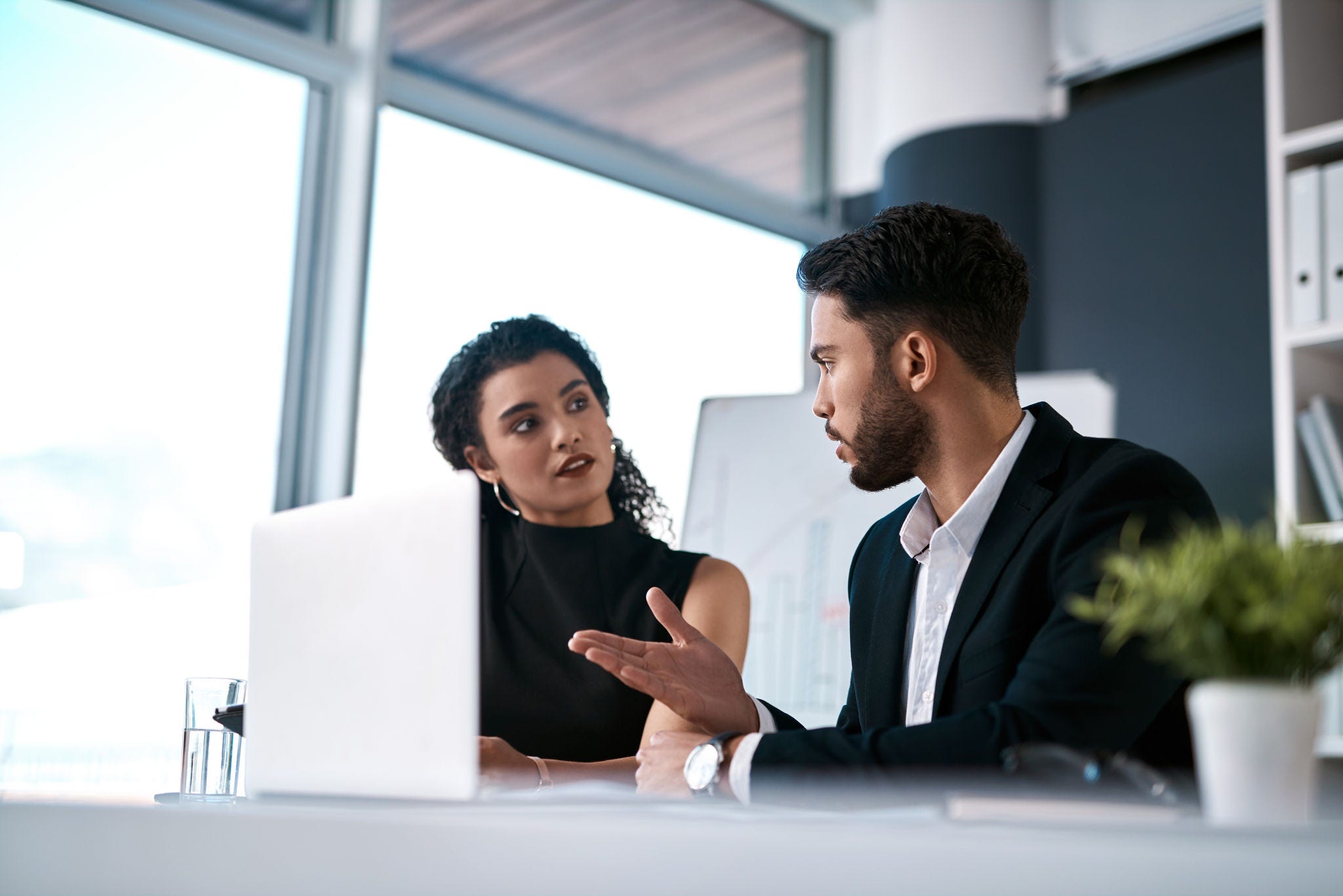 Serious, business meeting and people with laptop for performance review, communication and feedback. Corporate team, man and woman with computer in office for discussion and collaboration on project.