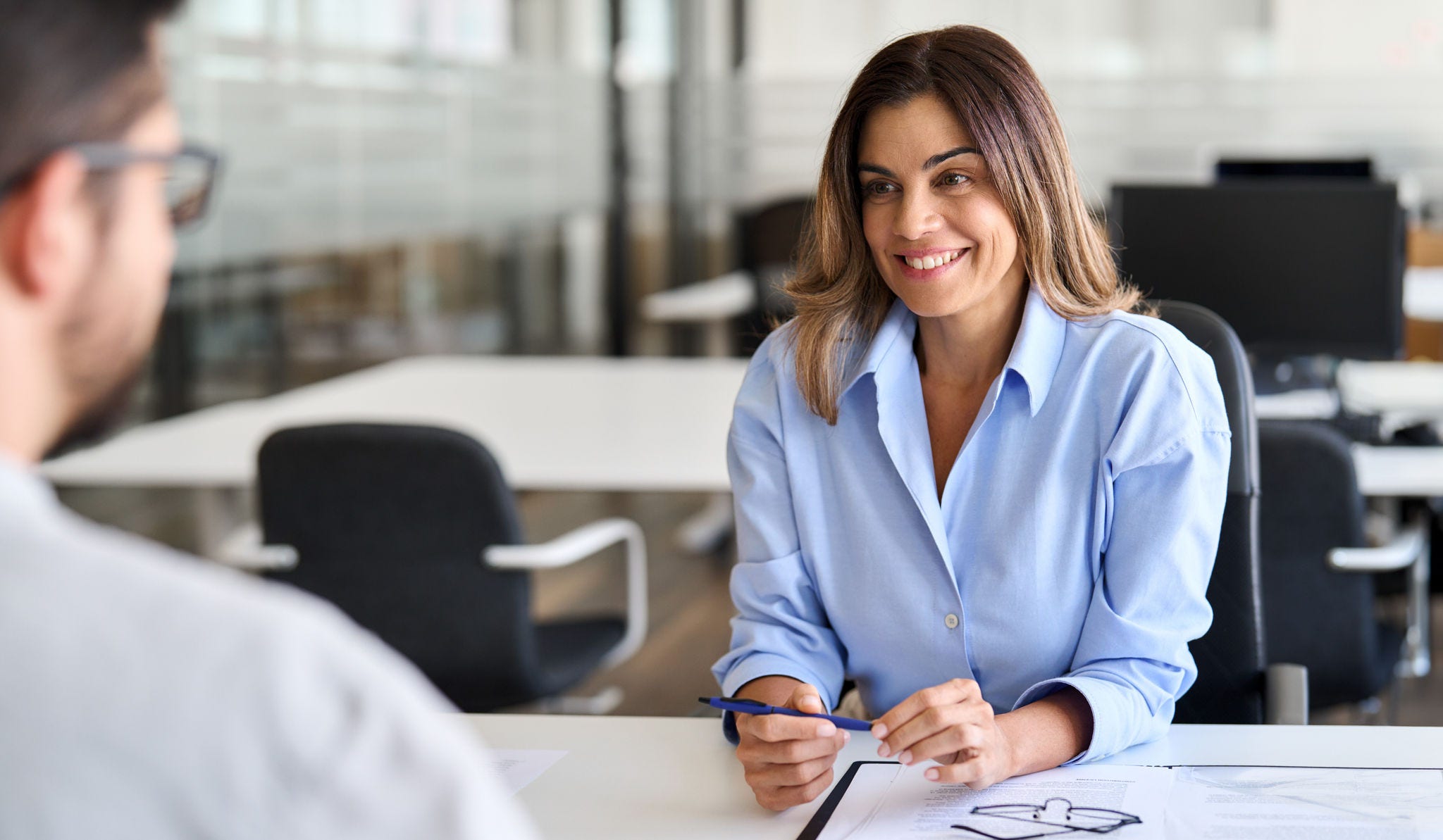 Smiling professional female hr having job interview meeting with male recruit. Happy middle aged business woman financial advisor, bank manager consulting client working in corporate office.